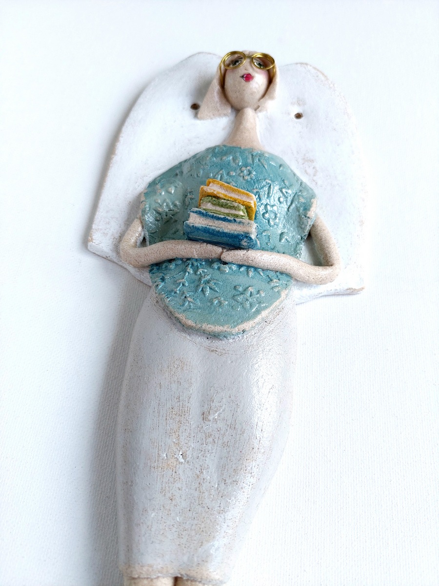 Figurka anioła trzymająca stos książek