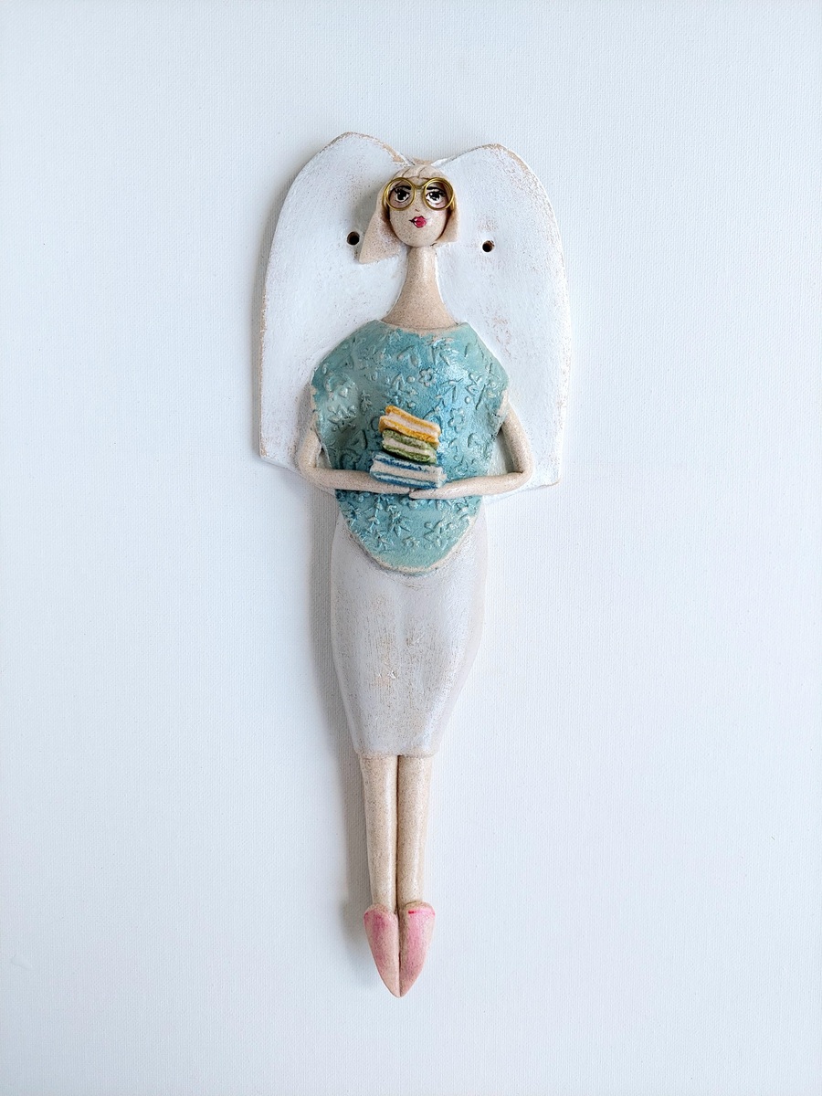 Figurka anioła trzymająca stos książek