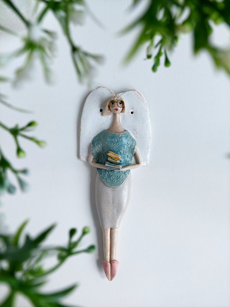 Figurka anioła trzymająca stos książek