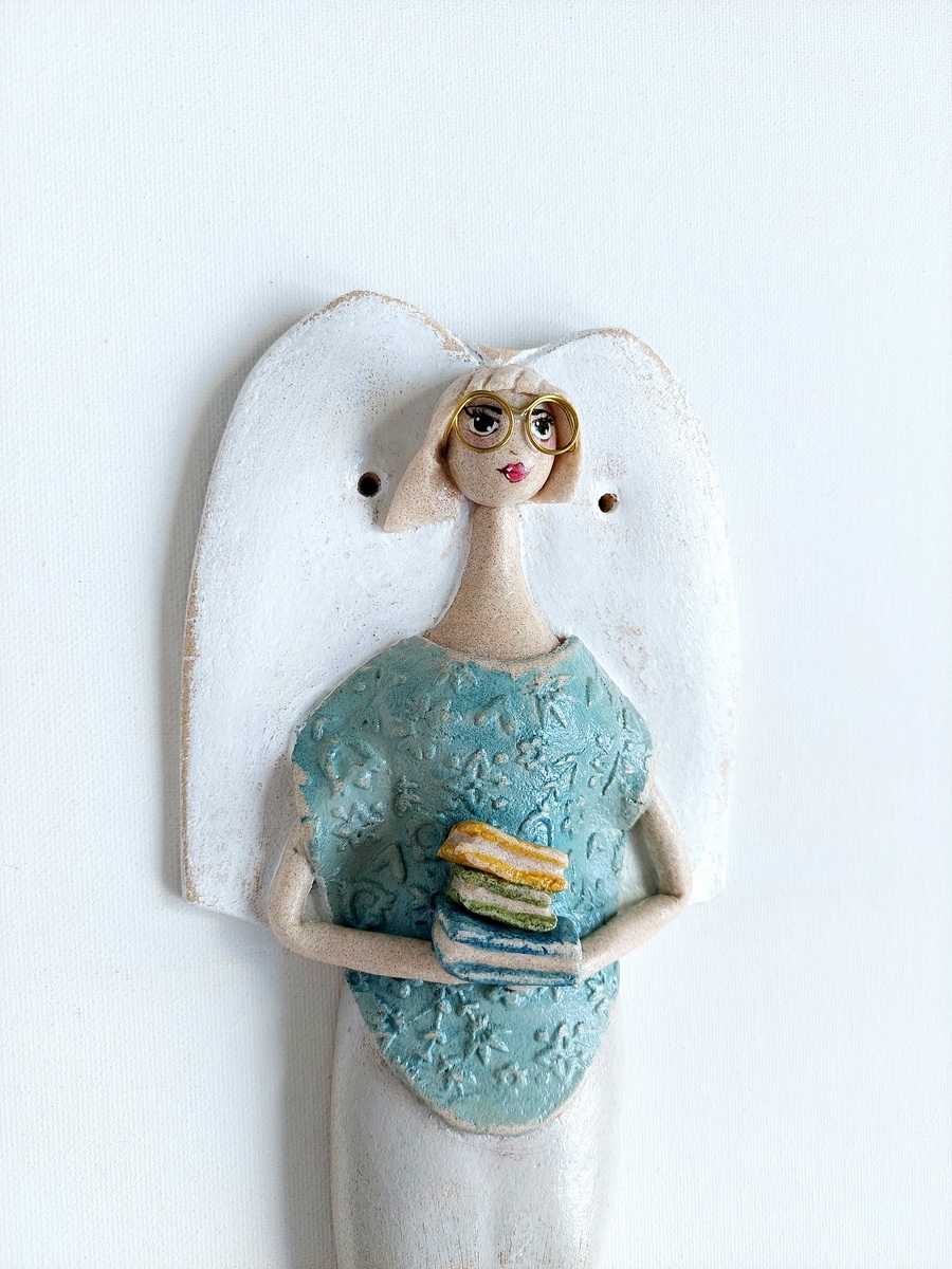 Figurka anioła trzymająca stos książek