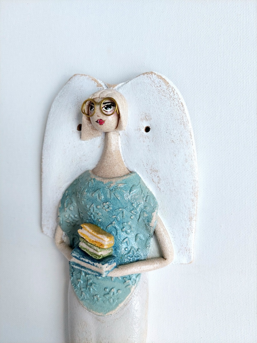 Figurka anioła trzymająca stos książek