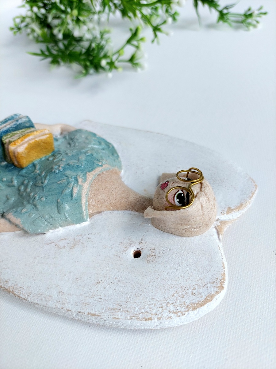 Figurka anioła trzymająca stos książek