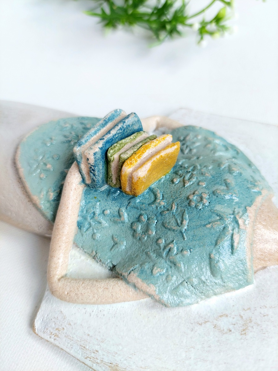 Figurka anioła trzymająca stos książek