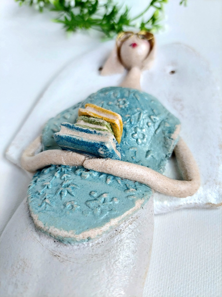 Figurka anioła trzymająca stos książek