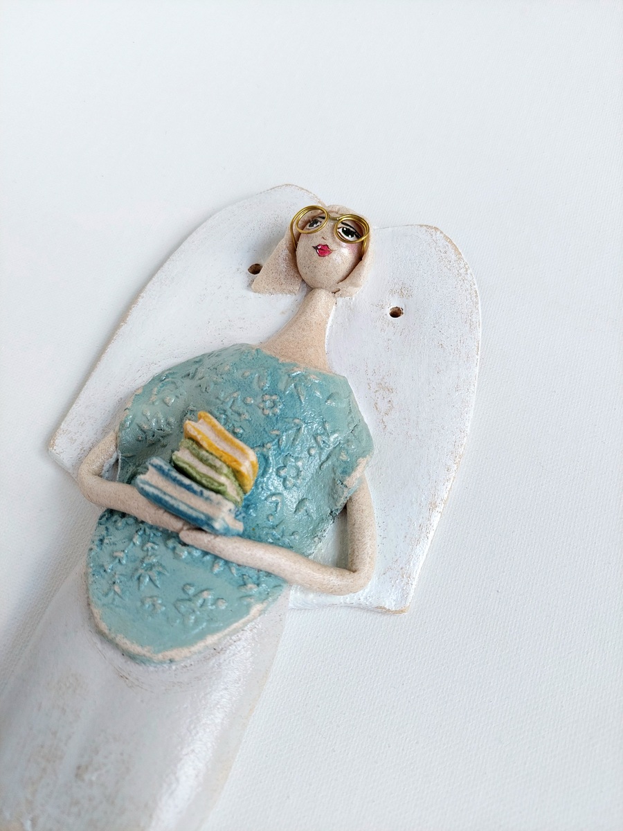 Figurka anioła trzymająca stos książek